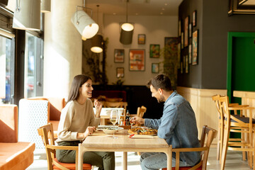 A joyful couple enjoying a delightful meal together at a cozy restaurant during a sunny afternoon