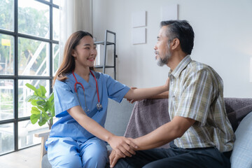Young female doctor comforting a senior male patient during a home visit, showing empathy and trust...