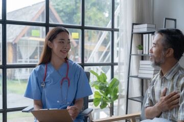 Caring young doctor listens to an elderly patient during a home visit, showing empathy and trust in...