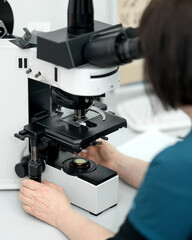 Laboratory technician examines sample under microscope. High-precision medical analysis and scientific research. Laboratory equipment. Microscopy. Side view. Soft focus. High quality photo