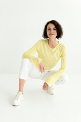 Portrait of woman wearing casual yellow sweatshirt sitting isolated on white background
