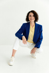 Portrait of business woman wearing casual yellow sweatshirt and blue suit sitting isolated on white background