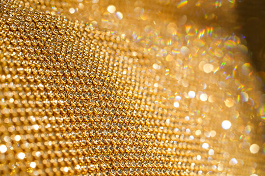 Gold lace with rhinestones shimmers, creating an impression of luxurious texture. Perfect for background or concept of elegance and wealth. Suitable for topics about fashion, jewelry, designer details