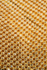 Gold lace with rhinestones shimmers, creating an impression of luxurious texture. Perfect for background or concept of elegance and wealth. Suitable for topics about fashion, jewelry, designer details