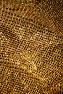 Gold lace with rhinestones shimmers, creating an impression of luxurious texture. Perfect for background or concept of elegance and wealth. Suitable for topics about fashion, jewelry, designer details