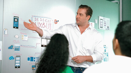 Professional smart businessman present Ux and Ui design to marketing team. Project manager sharing idea about business plan. Diverse business team working together to brain storm idea. Manipulator.