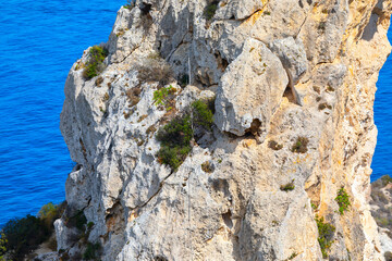 Rugged cliff with rope for climbing. Coastline rock on the Island
