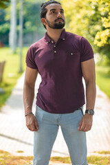 Close-up portrait of a confident, handsome, bearded Asian-Indian man with a ponytail. He's gazing...