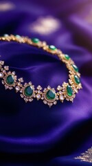 Fototapeta premium Gold choker necklace with emerald stones placed on a deep sapphire blue satin fabric, with a royal purple-to-sapphire gradient background and faint candlelight, Copy space, happy Diwali background