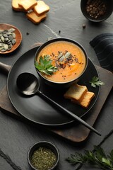 Delicious pumpkin soup with spices on dark textured table, above view
