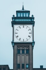 Historic clock tower in a cityscape on an overcast day highlighting traditional architecture details