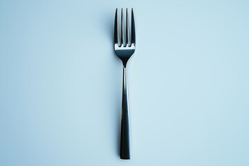 A modern stainless steel fork positioned upright against a light blue background