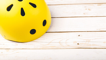 Yellow helmet on wooden background. Child's outdoors activity safety protection: rollers, bicycle,...