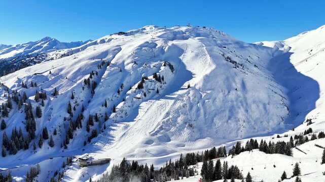 St Anton am Arlberg, Austria: Aerial view of famous bustling ski resort in Tyrolean Alps. Snow-covered slopes with ski runs, sunny day with clear blue sky - landscape panorama of Europe from above
