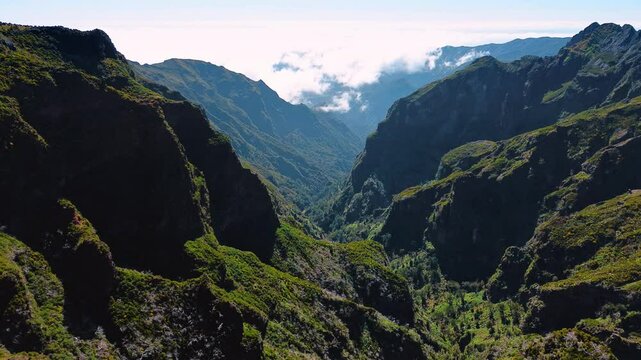 Breath-taking view of huge mountains overgrown with mosses. Sun dazzles the scenery at backdrop. The Madeira Islands rocks, Portugal. Aerial view.