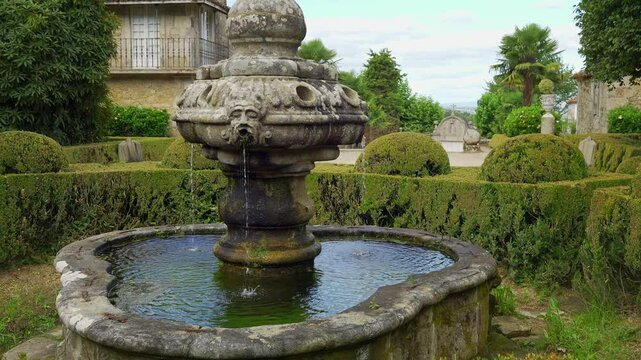 Beautiful old stone fountain with gardens around green plants, Pazo de Oca, Galicia.