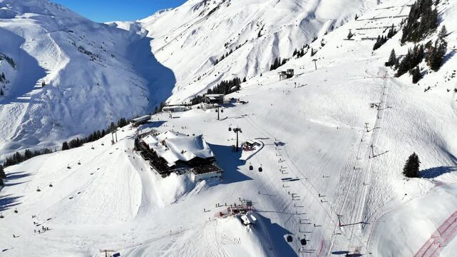 St Anton am Arlberg, Austria: Aerial view of famous bustling ski resort in Tyrolean Alps. Snow-covered slopes with ski runs, sunny day with clear blue sky - landscape panorama of Europe from above
