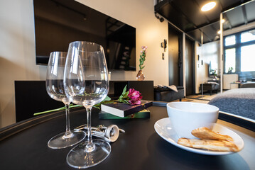 Wine glass and book on table in luxury hotel room. Wine glass and pancakes on the table. Modern furnished kitchen and a dining room. Modern kitchen connected to the living room in modern apartment.