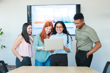 Smiling young latin businesspeople sharing ideas and strategies, promoting teamwork in a modern...