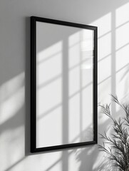 A monochrome minimalist artwork in a black frame, its stark simplicity highlighted by shadows and light on the surrounding wall.