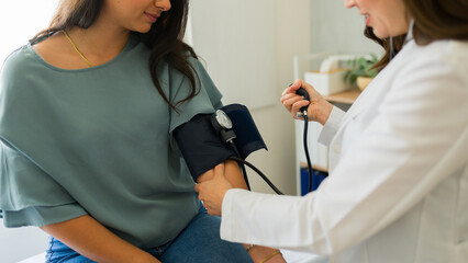Closeup of a doctor measuring blood pressure of young woman during medical check-up