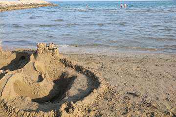 sandcastle by the sea built during summer with waves touching the beach