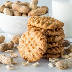 A close up of a stack of homemade peanut butter cookies with a bowl of peanuts.