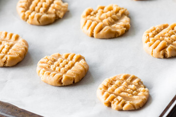 Fresh raw peanut butter cookies on a parchment lined cookie sheet.