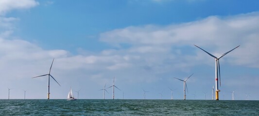 Voilier navigant entre les éoliennes offshore du parc éolien en mer de Saint-Nazaire, Loire Atlantique, France