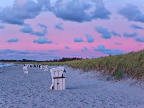 autumn pink sun set at the beach with white beach chairs