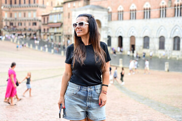 Happy smiling woman    using a phone at Piazza del Campo ,at Siena , Tuscany  Concept of Italian gastronomy and travel.