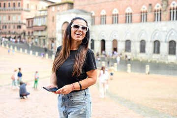 Obraz premium Happy smiling woman using a phone at Piazza del Campo ,at Siena , Tuscany Concept of Italian gastronomy and travel.