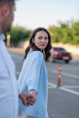 Fototapeta premium A young dark-haired girl leads a man by the hand and looks at him with loving eyes