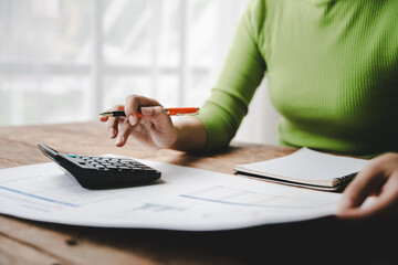 Close-up of young woman's hand working with tax and financial accounting documents. Company income...