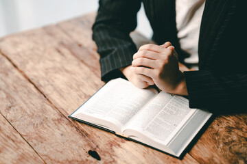 Cropped view of young woman praying with bible on table Confession concept Pray and talk with God