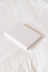 White book mockup on white hotel bed