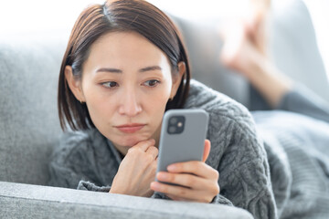 スマホを持って悩む女性