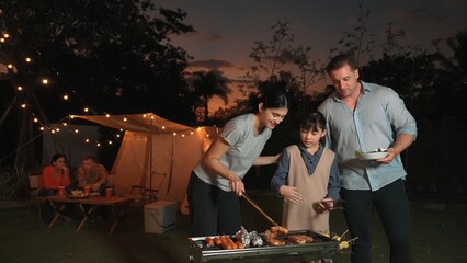 Family celebrate holiday in garden, Mother and child grill food for family member. Outdoor camping...