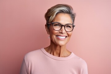 Portrait of smiling senior woman with eyeglasses against pink background