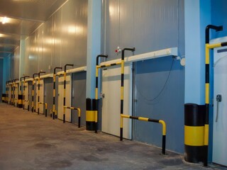 A corridor with sliding doors leading to cold storage chambers made of sandwich panels.