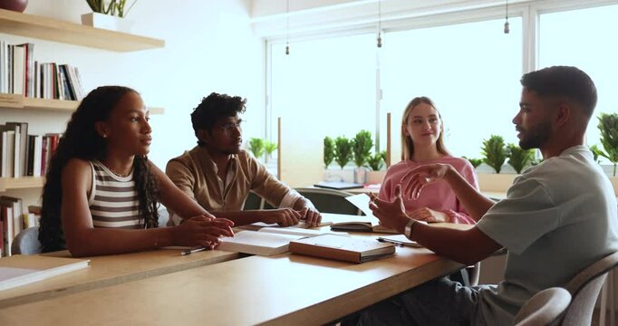 Multiethnic group of students talking in library, discussing training group tasks, education process, brainstorming on creative ideas, working on home assignment, class project together