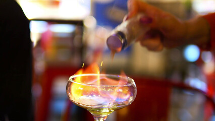 Making process of Burning cocktail absinthe by woman bartender in bar. Nightlife entertainment