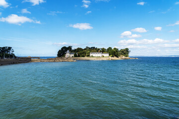 L'île Tristan, baignée par les eaux de la mer d'Iroise, se détache sous un ciel bleu éclatant. À marée haute, ce joyau de Douarnenez se révèle dans toute sa splendeur estivale.
