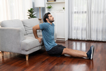 Athletic body and active sporty man using furniture for effective targeting muscle gain exercise at gaiety home exercise as concept of healthy fit body home workout lifestyle.