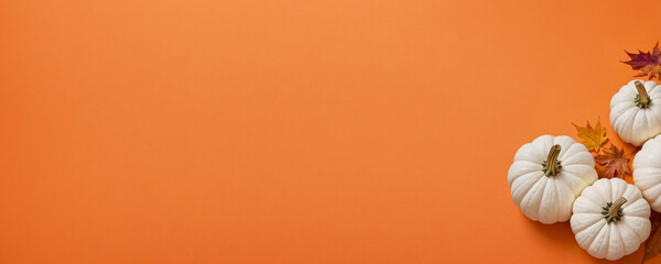 Obraz premium White pumpkins and autumn leaves on a flat orange background. Concept for Thanksgiving, Harvest Festival or Halloween celebrations. Autumn flat lay for banner with copy space for text. Top view.