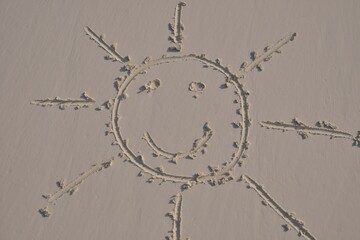 Sun face drawn in the sand