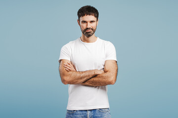 Confident, positive bearded man wearing white t shirt looking at camera with crossed arms