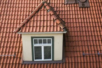 Top view of dormer window on old terracotta roof of residential apartment building, Tallinn,...