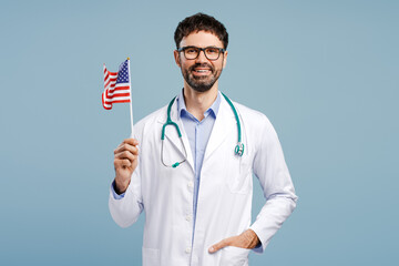 Confident man, professional doctor wearing white coat, eyeglasses and stethoscope holding USA flag