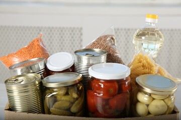 Different food products for donation in box indoors, closeup